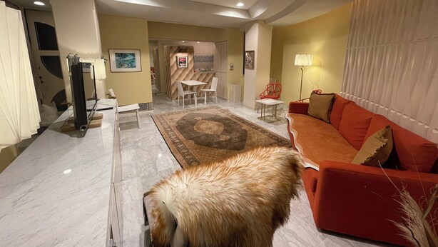 A modern living room with a red sofa, a coffee table, and a dining area with a white table and chairs.