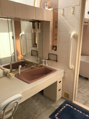 Une salle de bain moderne avec un grand miroir, deux vasques et une barre d’appui.