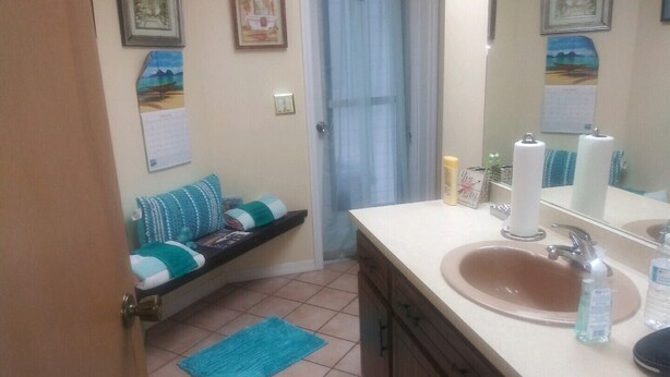 A bathroom with a sink, mirror, and a shelf with towels and toiletries. - Spacious Corner House  NO POOL HOWEVER BEAUTIFUL  PROFESSIONAL POOL TABLE (Cape Coral)