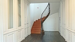 Un pasillo con una escalera de madera que conduce a una puerta.