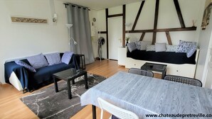 Una sala amueblada con sofá, una mesita, una mesa de comedor y una cama con cabecera.