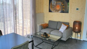 A modern living room with a grey sofa, a glass coffee table, and a lamp. - Holiday home Callants` Lodge (Callantsoog)