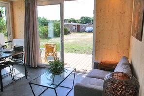 Un salon avec une table basse en verre, un canapé et un coin repas avec des chaises.
