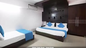 A Deluxe Triple Room with a large bed, two single beds, a dark headboard, and a wardrobe. - HOTEL GRAND AEROCITY BY TRIO (New Delhi)