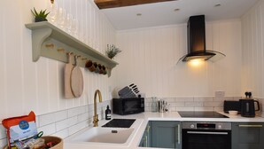 Una cocina moderna con armarios blancos, estufa negra y pileta de acero inoxidable.