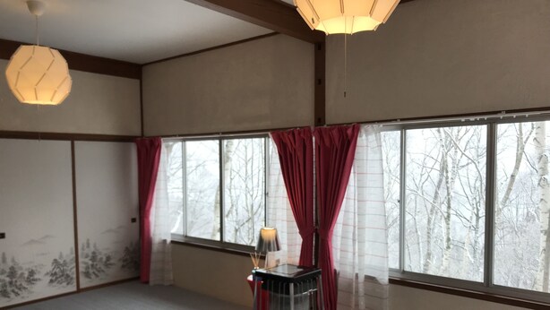 Una habitación con ventanas amplias, una cama, un calentador y una lámpara.