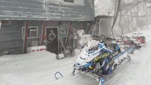 Un edificio cubierto de nieve con una moto de nieve estacionada frente a él.