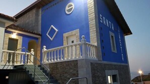 A building with a blue facade, a white balcony railing, and a stone base.