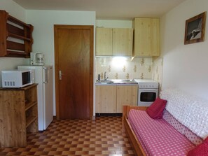 Eine kompakte Küche mit Mikrowelle, Kaffeemaschine, Spüle und Herd.