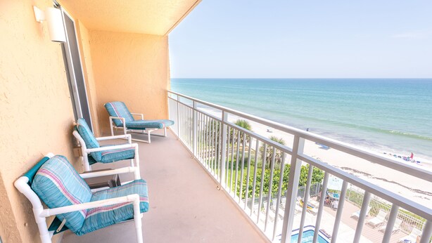 A balcony with two lounge chairs and a pool area. - Oceanfront Corner Unit 2BR Condo 5th Floor Balcony Views, 501 (Indian Harbour Beach)