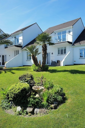 Stunning two-story house with a beautifully maintained lawn and garden, featuring a staircase and a variety of plants.