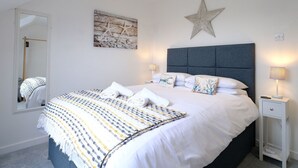 Un dormitorio con una cama grande, un adorno con forma de estrella en la pared, un cuadro y una mesita de noche con lámpara.