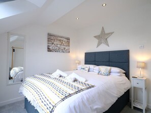 Cozy retreat with a large bed, bedside table, and nautical artwork.