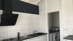 Eine moderne Küche mit weißen Schränken, einer schwarzen Arbeitsplatte und einem eingebauten Ofen.