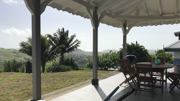 Ein überdachter Außenbereich mit Blick auf eine hügelige Landschaft.