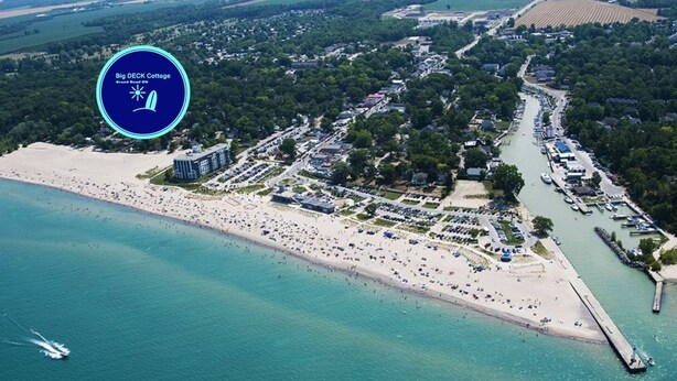 An aerial view of Big DECK Cottage with a beach, parking areas, and a marina. - Big DECK Cottage, 3-min walk to BEACH- 4 bdrms, 1.5 baths 7 beds, parking 3 cars (Grand Bend)