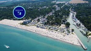 An aerial view of Big DECK Cottage with a beach, parking areas, and a marina.