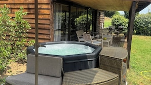 A hot tub with wicker furniture and an umbrella in a backyard setting.