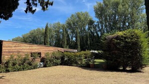 A building with a sloped roof, surrounded by gravel, trees, and shrubs.
