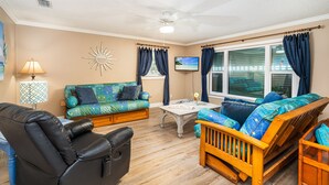 Un salon comprenant un canapé, un fauteuil, une table basse et un téléviseur.