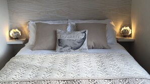 A neatly made bed with a patterned quilt, two pillows, and two bedside lamps. - A delightful fisherman’s cottage with uninterrupted sea views. (Staithes near Whitby)