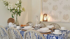 A dining table set with white plates, bowls, and glasses, surrounded by white chairs with decorative bows. - A delightful fisherman’s cottage with uninterrupted sea views. (Staithes near Whitby)