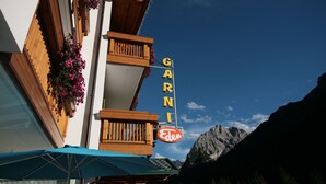 A hotel named 'GARNI' with a balcony, wooden facade, and mountain backdrop. - Garnì Eden (Canazei)