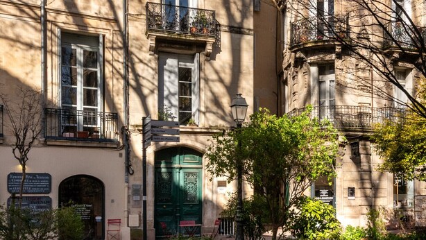 A historic building with multiple windows, a green door, and a small balcony.