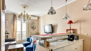 A modern kitchen with a marble countertop, a built-in TV, and pendant lighting.