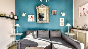 A modern living room with teal walls, a large sectional sofa, a decorative mirror, and a chandelier.