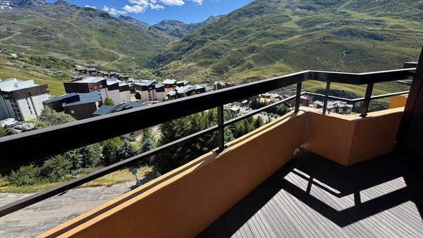 Un balcon offrant une vue sur un paysage montagneux et un petit village situé en contrebas.