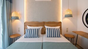 A double bed with striped pillows, a wooden headboard, a wall-mounted air conditioner, and two hanging lights.