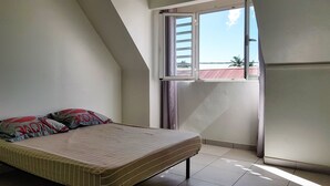 Una habitación pequeña con cama, ventana y puerta.