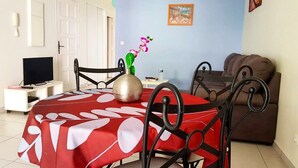Un comedor con mantel rojo, un florero con flores y un sofá marrón.