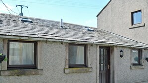 A two-story building with a stone facade, a dark brown door, and multiple windows. - 2 bedroom accommodation in Whitehaven (Whitehaven)