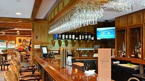 Eine Bar mit Holztischen, einer Theke und einem Fernsehbildschirm.