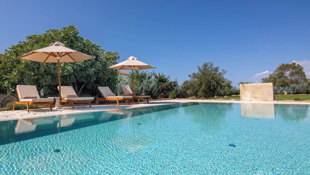 A clear blue pool with lounge chairs and umbrellas, surrounded by greenery. - Villa Rose Corfu, Villa (Acharavi)