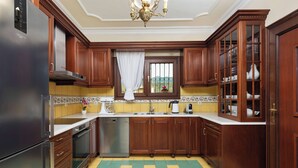 A kitchen with wooden cabinets, a stainless steel refrigerator, a dishwasher, and a checkered floor. - Villa Rose Corfu, Villa (Acharavi)