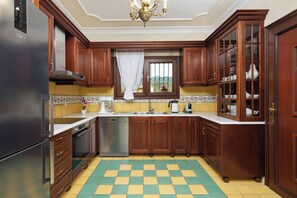 A kitchen with wooden cabinets, a stainless steel refrigerator, a dishwasher, and a checkered floor. - Villa Rose Corfu, Villa (Acharavi)