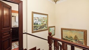 A wooden staircase with a handrail, a painting of a coastal scene, and a door leading to a room with a tiled floor. - Villa Rose Corfu, Villa (Acharavi)