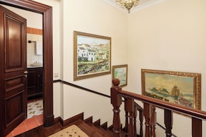 A wooden staircase with a handrail, a painting of a coastal scene, and a door leading to a room with a tiled floor. - Villa Rose Corfu, Villa (Acharavi)