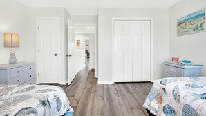 A bedroom with two beds, a nightstand, a lamp, and a painting on the wall.