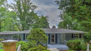 A two-story house with a covered porch, surrounded by well-maintained greenery and a clear sky. - Spectacular Views! -Great Location-Hot Tub-Dreamy Porch & Sun Room-Fenced Yd! (Arden)