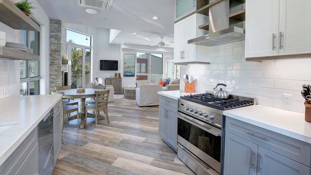 A modern kitchen with a central island, built-in appliances, and a dining area with a view.