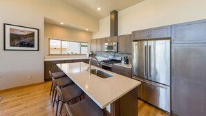 A modern kitchen with a central island, stainless steel appliances, and a large window providing natural light. - Hawks Landing - New, Modern, Views, Billiards! (Hood River)
