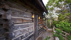 A rustic log cabin with a wooden porch and lanterns. - Stay at these upscale, historic cabins set in New Braunfels near Guadalupe River (New Braunfels)