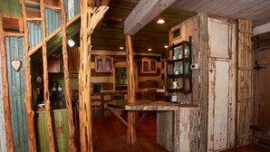 A rustic kitchen with wooden cabinets, a central island, and a heart-shaped decoration on the wall. - Stay at these upscale, historic cabins set in New Braunfels near Guadalupe River (New Braunfels)