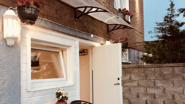A patio with a table and chairs, a white door, and hanging flower baskets.