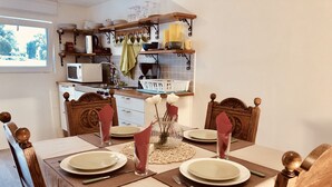 A dining table set for four with plates, glasses, and a vase with flowers.