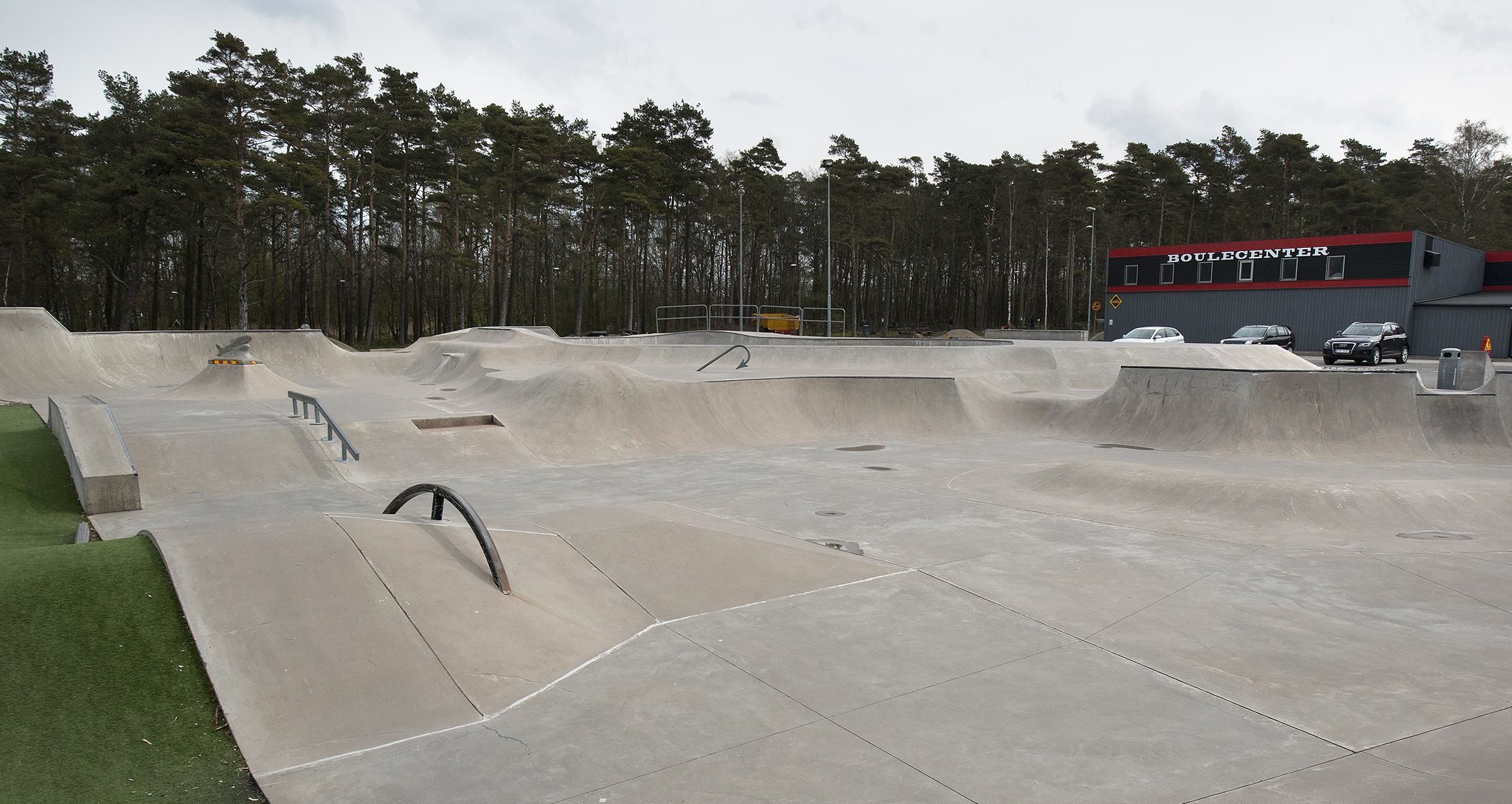 Un skatepark avec différentes rampes et, au fond, un bâtiment portant l’inscription « BOULCENTER ».